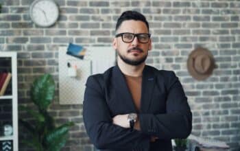 a man in a suit standing in front of a brick wall